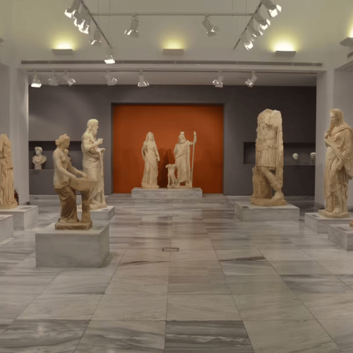 Shiny floor of a museum with a few statues around