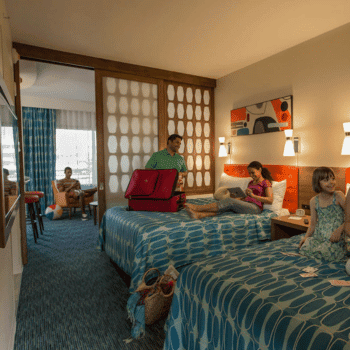 🏖️ Cabana Bay Beach Resort Review with Volcano Bay View – A Fantastic Family Hotel 13 Family enjoying their stay in a colourful suite at Cabana Bay, with two kids on the beds and parents in the living area
