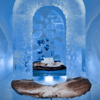 Icehotel bedroom with carved walls and fur bedding on an ice bed