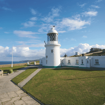 White lighthouse with connected buildings overlooking the sea on a sunny day