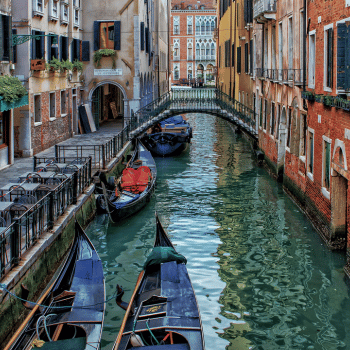 ✈️ Flight Search and Travel Deals All in One Place – Compare, Save, Go! 17 Traditional gondolas floating in a narrow canal between colourful old buildings in Venice, Italy
