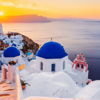 Whitewashed cliffside houses with blue-domed churches overlooking the sea in Santorini, Greece