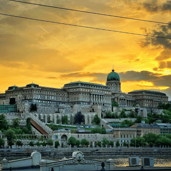 Compare Flights and Travel Essentials 15 Buda Castle in Budapest, Hungary, glowing at sunset with dramatic golden skies above.