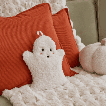 🎃 Spooky Season Travel Deals & Haunted Adventures ✈️👻 23 Cream OHS ghost-shaped microwaveable hottie on a cosy sofa with orange cushions and a plush pumpkin.