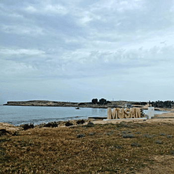 Ayia Napa in May – A Mum & Daughter Escape 🌊☀️ 21 Wide view of Musan Beach with sandy shore, calm sea, and the Musan sign in the distance