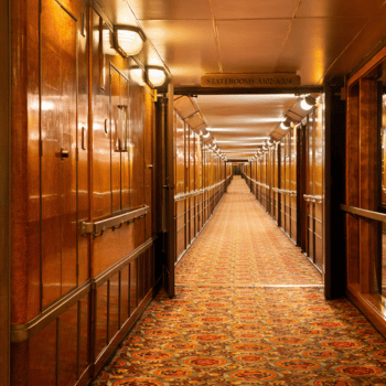 Compare Flights and Travel Essentials 14 Long, wood-paneled hallway inside The Queen Mary ship with patterned carpet and cabin doors