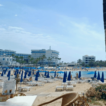 Ayia Napa in May – A Mum & Daughter Escape 🌊☀️ 30 Crowded sandy beach lined with blue umbrellas and sun loungers, resort buildings in the background