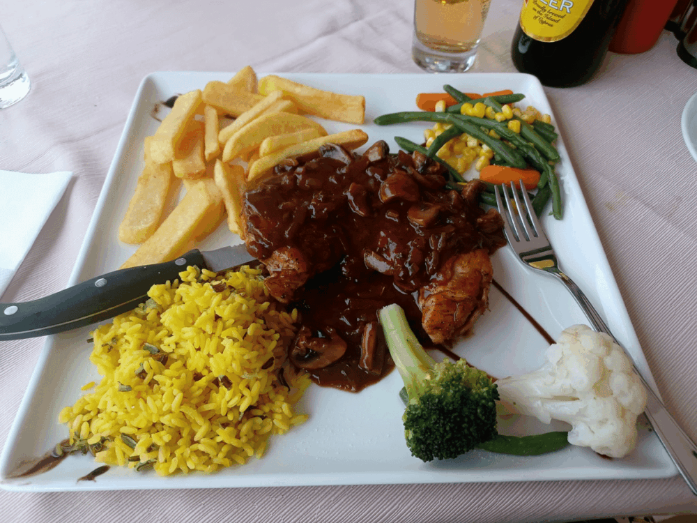 Steak with mushroom sauce, chips, rice and vegetables
