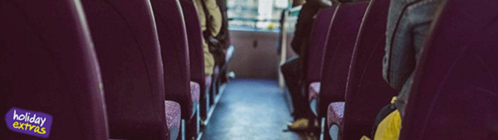 Travel Offers & Discounts 7 Interior view of a coach with purple seats and passengers, featuring the Holiday Extras logo in the corner.