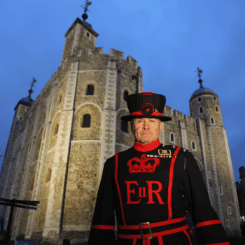 🎃 Spooky Season Travel Deals & Haunted Adventures ✈️👻 16 Yeoman Warder standing in front of the Tower of London at dusk