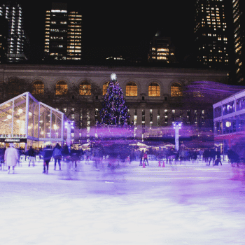Compare Flights and Travel Essentials 45 People skating at Bryant Park Winter Village ice rink surrounded by lights and festive stalls in New York City