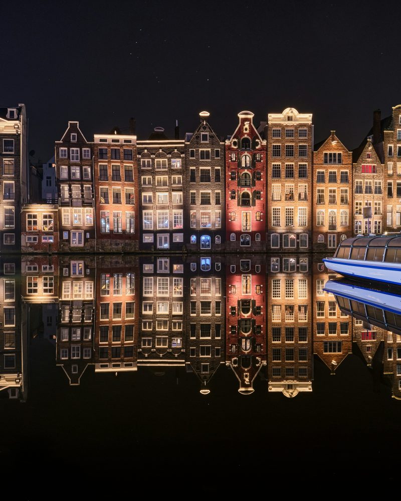 Compare Flights and Travel Essentials 109 Amsterdam canal houses reflected in still water at night