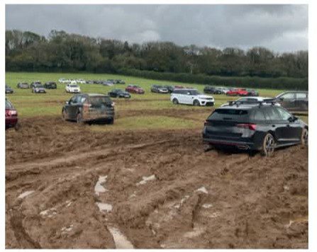 Cars parked in a muddy, unsecured field used by an unofficial airport parking operator, highlighting the risks of choosing unvetted parking services.