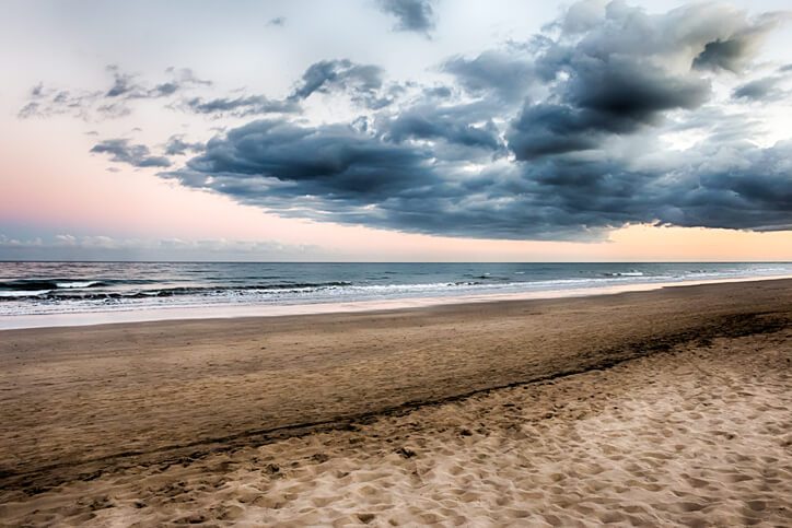 Compare Flights and Travel Essentials 76 Sunset over Maspalomas Beach with soft waves and dramatic evening clouds