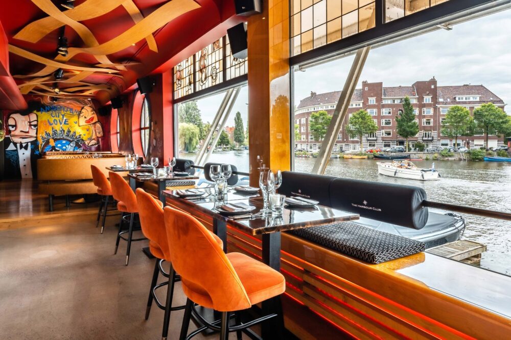 Compare Flights and Travel Essentials 108 Canal-side restaurant with floor-to-ceiling windows at Apollo Hotel Amsterdam
