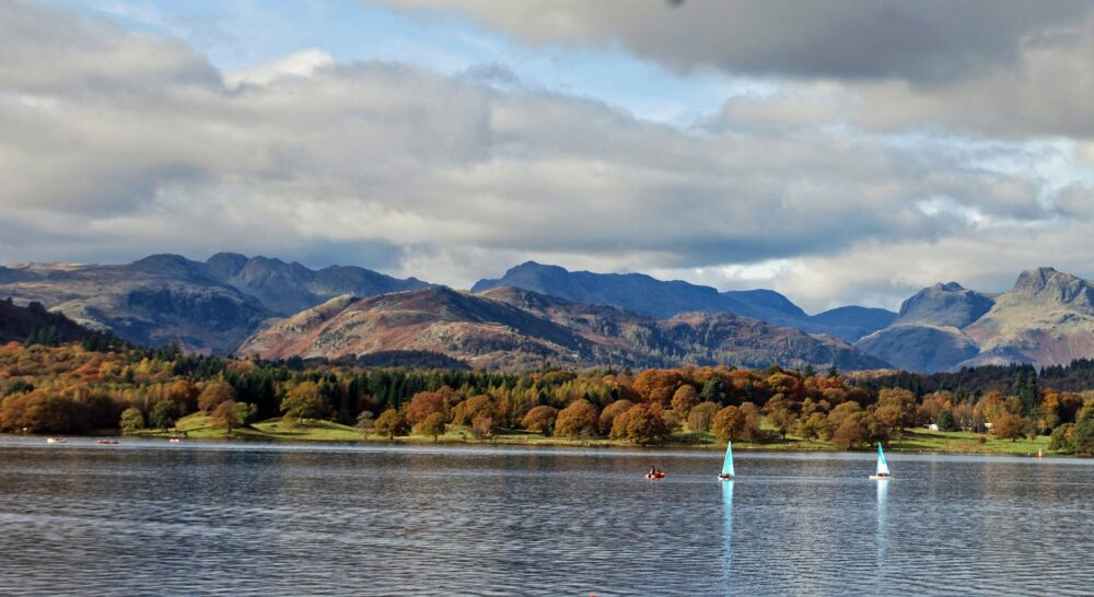 Compare Flights and Travel Essentials 88 Lake Windermere with sailing boats and autumn-coloured fells in the Lake District