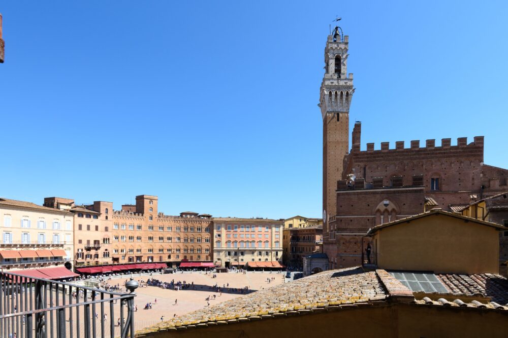 Compare Flights and Travel Essentials 28 View over Piazza del Campo with Torre del Mangia rising above historic brick buildings