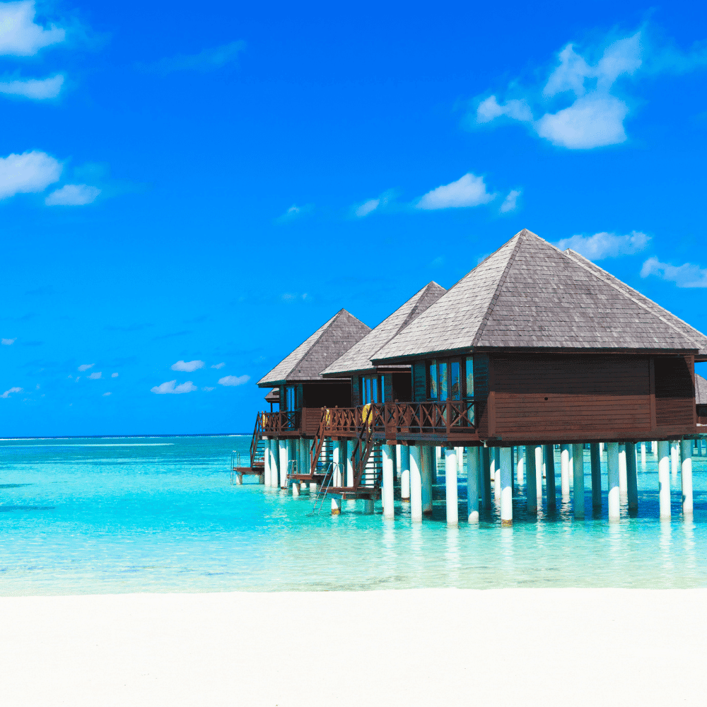 Overwater bungalows on wooden stilts above clear turquoise lagoon water
