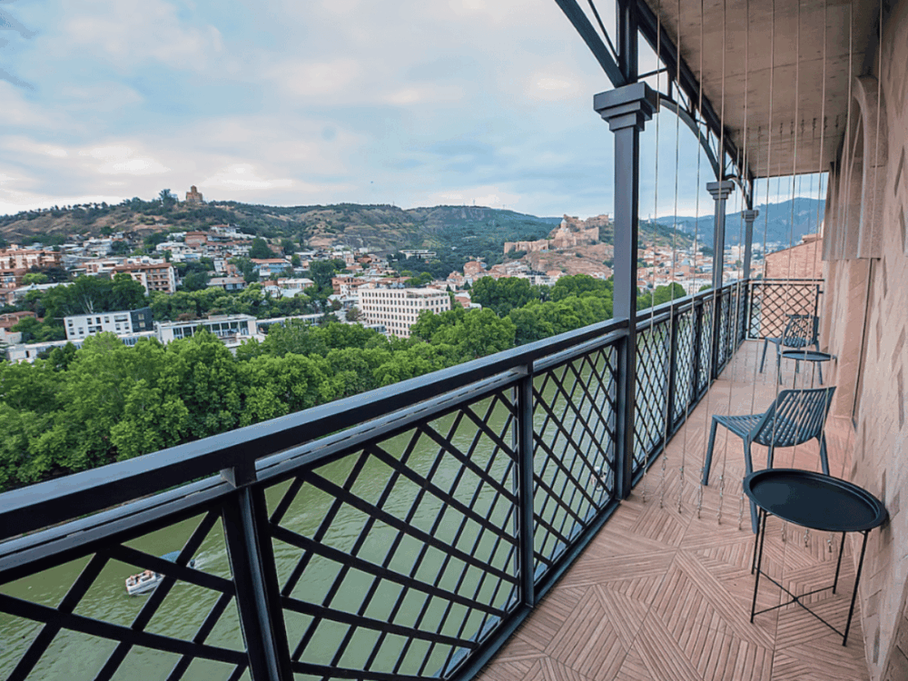 Are All-Inclusive Holidays Worth It? What’s Really Included (and What’s Not) 9 Balcony with chairs overlooking a river and historic city skyline at Sandali Metekhi Boutique Hotel