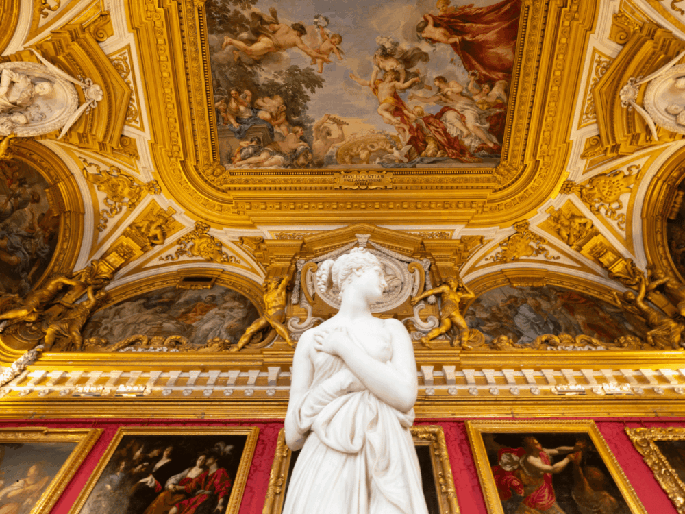 Marble statue beneath an ornate painted ceiling in an art gallery