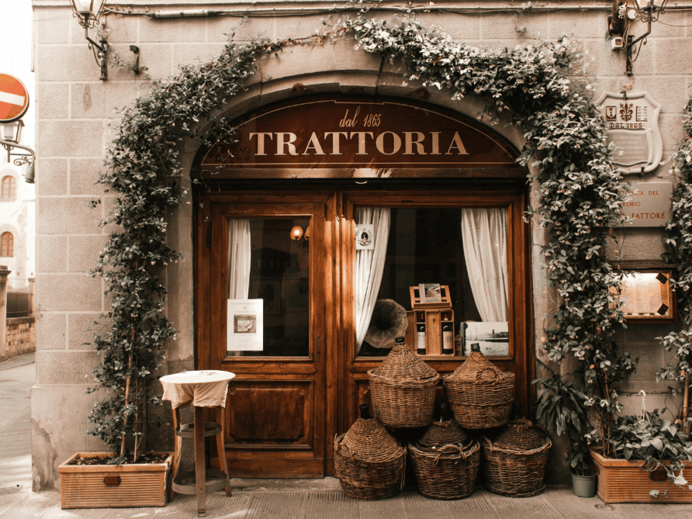 Traditional trattoria entrance with wooden doors and climbing plants