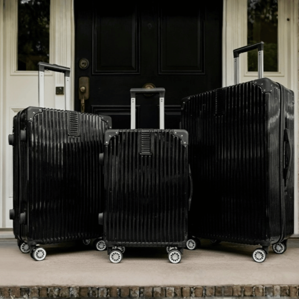 OHS 4 Wheel Hard Shell Suitcase 1 Black hard shell suitcase set with four wheels placed outside a home ready for travel