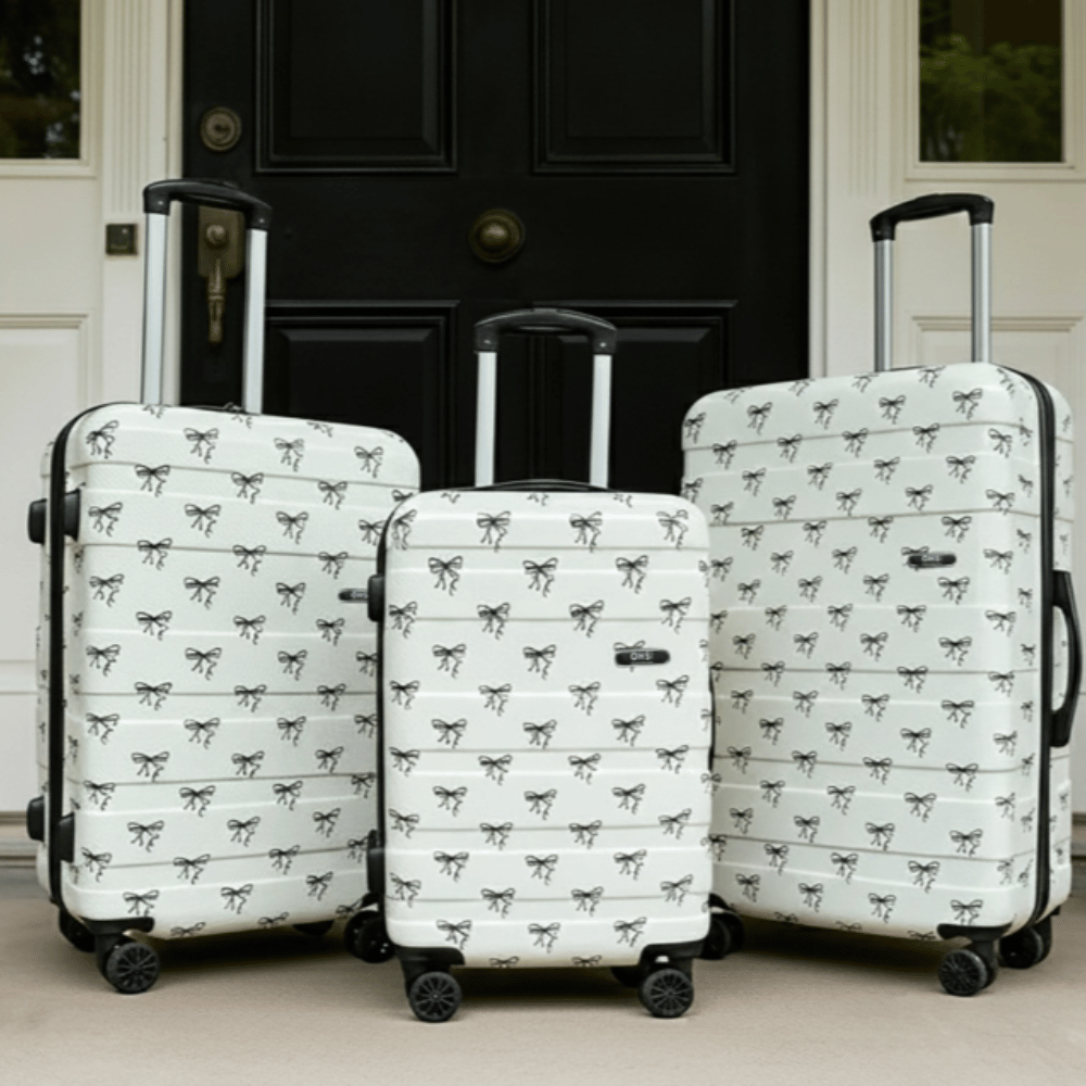 OHS 4 Wheel Hard Shell Suitcase 2 Hard shell suitcase set with bow print design and four wheels positioned outside before travel