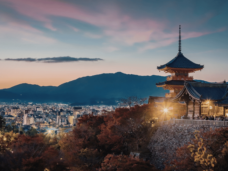 Traditional temple overlooking Kyoto city at dusk with mountains in the background