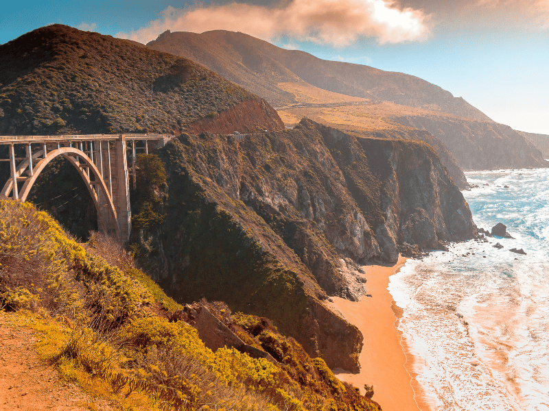Car Hire 5 Coastal bridge and rugged cliffs along the Pacific Coast Highway, USA.