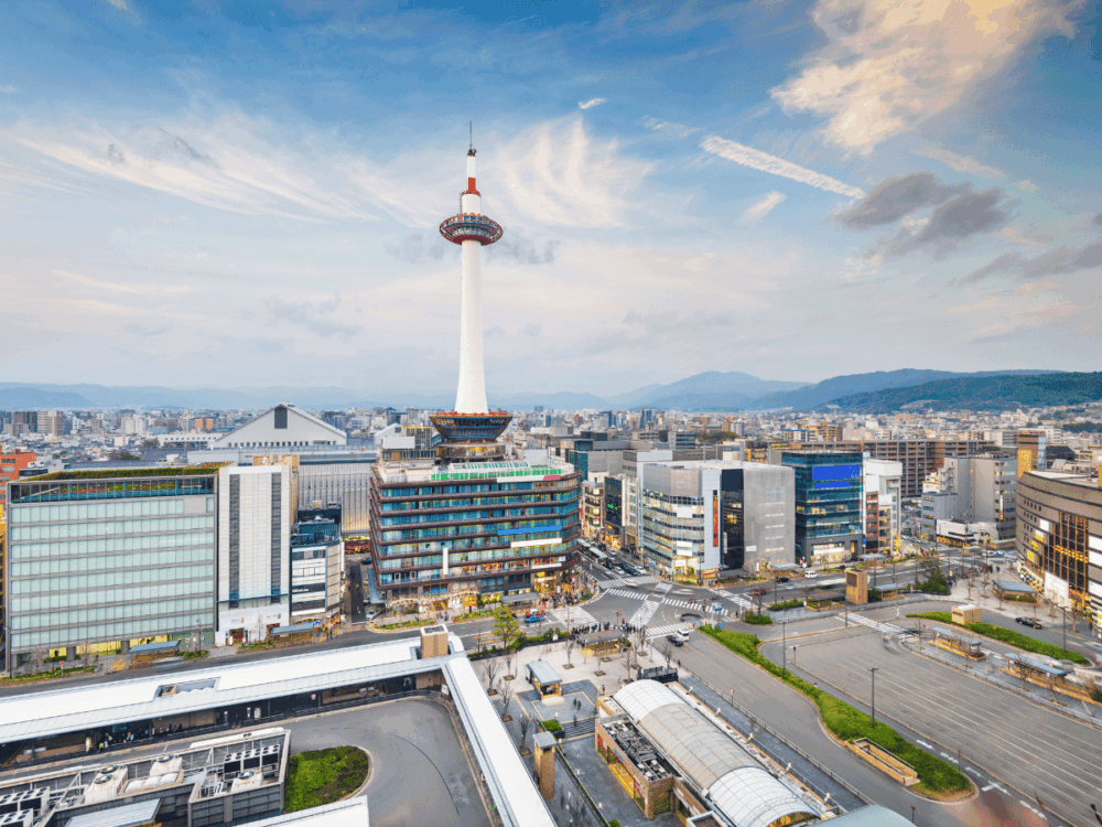 Kyoto Tower rising above the city skyline near Kyoto Station at sunset.