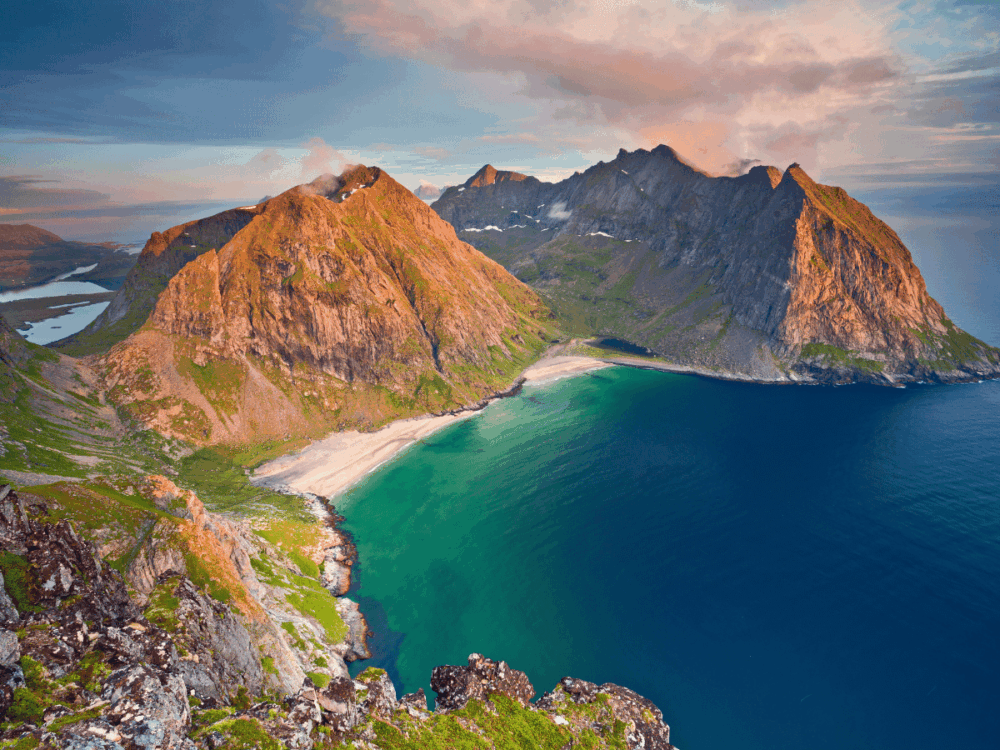 Mountain peaks, white sandy beach and turquoise sea in the Lofoten Islands, Norway.