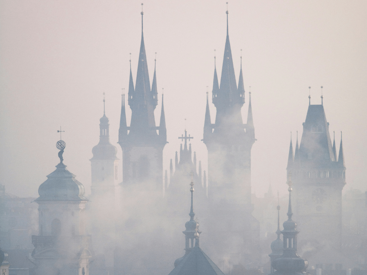 Prague skyline with church spires emerging through morning fog