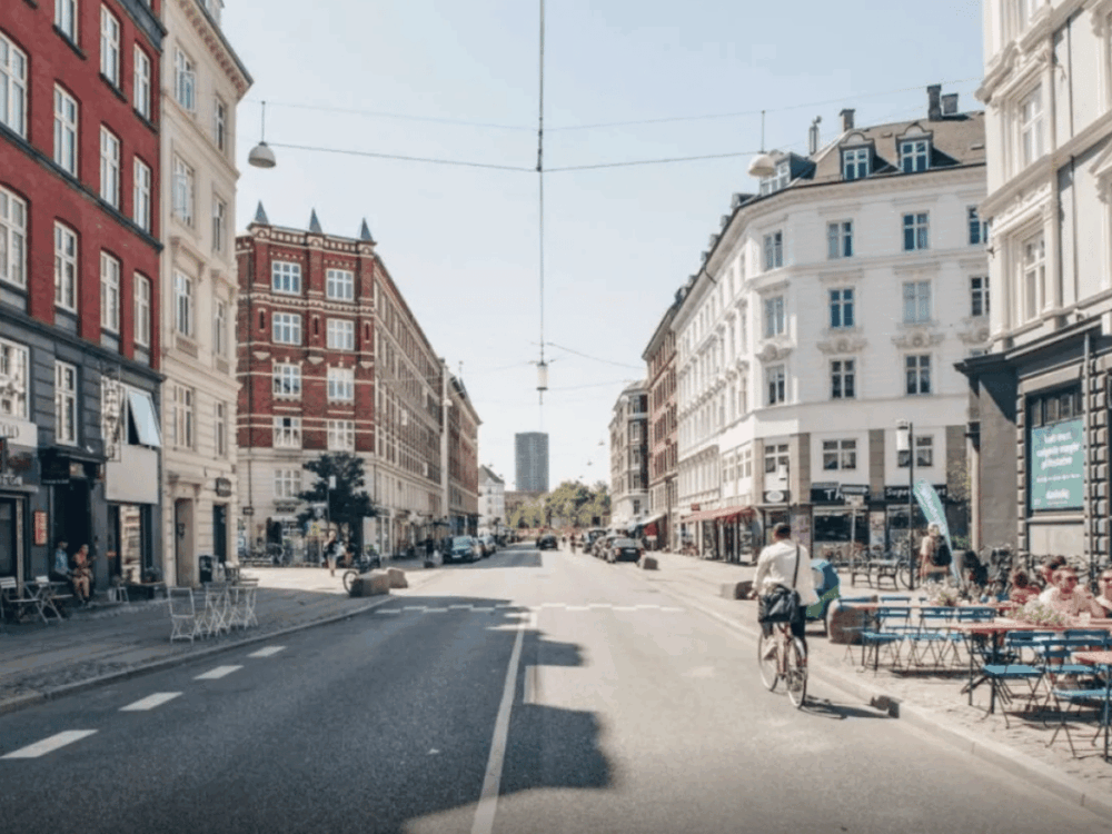 Vesterbro – Copenhagen's Coolest Neighbourhood 3 Street in Vesterbro with cafés, cyclists and historic buildings in Copenhagen.