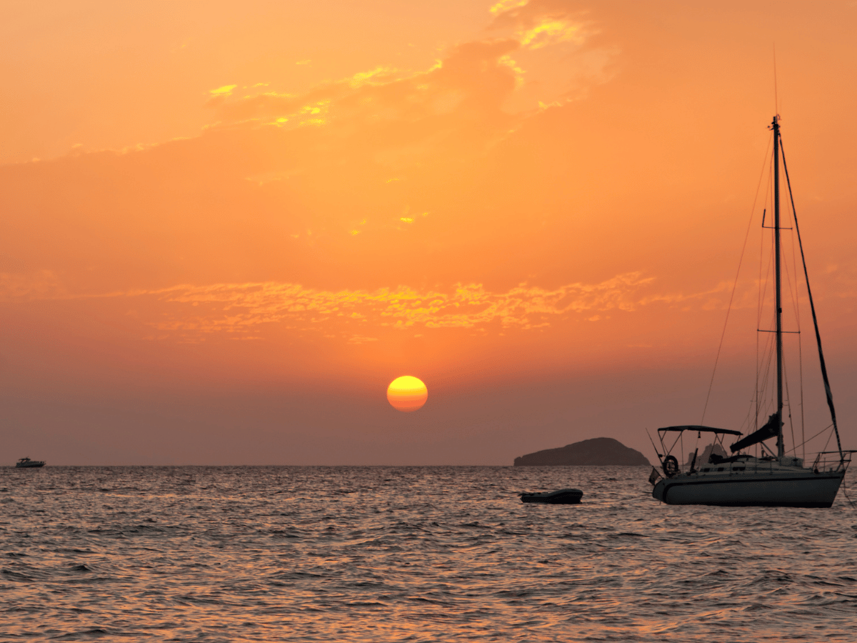 Orange sunset over the sea with yachts anchored off the coast of Ibiza.