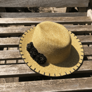 Front view of the Louche Kia Straw Trilby Hat with raffia pom-pom detailing.