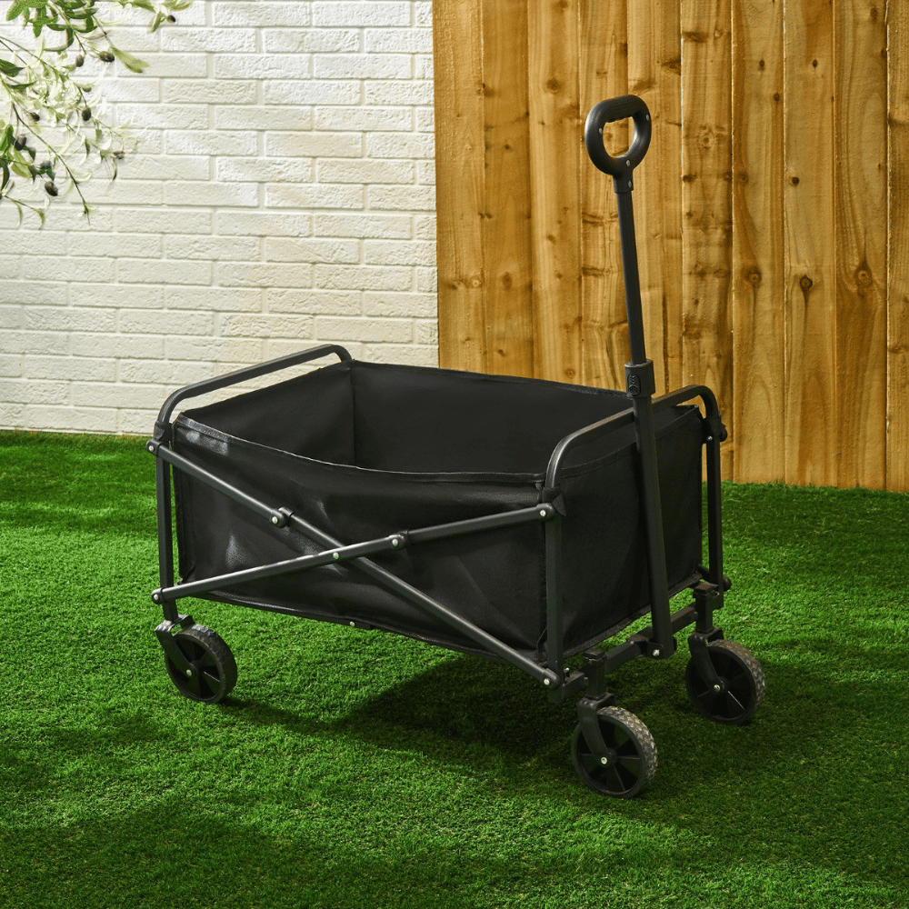 Black foldable camping trolley with four wheels and an upright pull handle on artificial grass.
