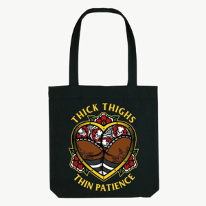 Black tote bag with handles and a printed Thick Thighs Thin Patience design featuring a figure and flowers.