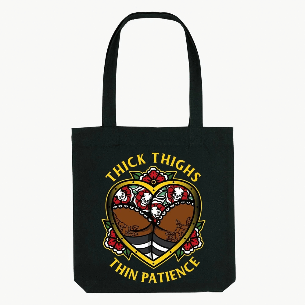 Black tote bag with handles and a printed Thick Thighs Thin Patience design featuring a figure and flowers.