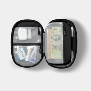 Open black Nomatic Navigator Tech Organizer showing mesh zippered pockets containing small accessories and banknotes, with a white pen secured at the side.